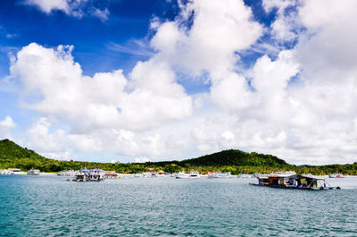 Boats sailing in sea against cloudy sky