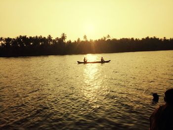 Silhouette people on boat in sea against sky during sunset