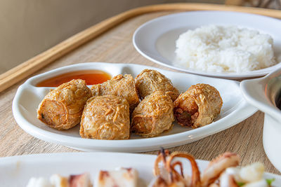 Close-up of deep fried crab meat rolls, chinese asia culture food in white plate on the table