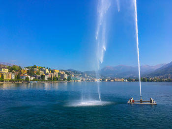 Fountain in lake against blue sky