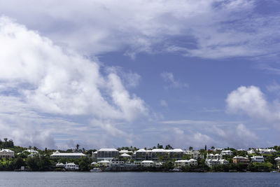 Scenic view of river by buildings against sky