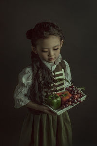 Girl looking away while standing against black background