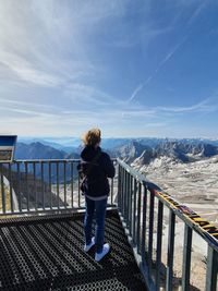 Rear view of woman standing on railing against mountain