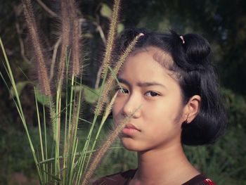 Close-up portrait of serious girl holding plants