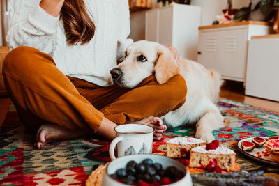 Low section of woman doing breakfast with dog at home