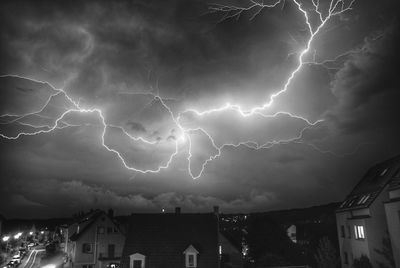 Low angle view of lightning in city against sky at night