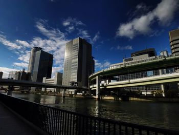 Bridge over river by buildings against sky in city