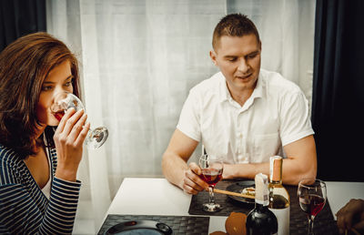 Man and woman having red wine at table