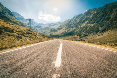 Empty road by mountains against sky