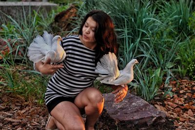 Young woman playing with pigeons on field