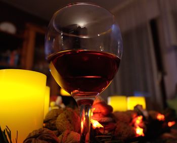 Close-up of red wine and lit tea light candles on table