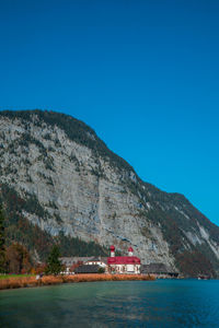 Scenic view of sea and mountains against clear blue sky