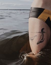 Midsection of man standing at shore against sky