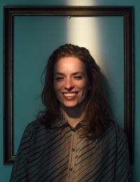 Mid adult woman standing against picture frame on wall