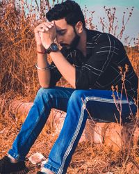 Young man looking at camera while sitting on field