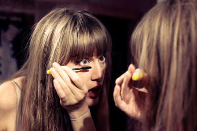 Woman applying mascara at home