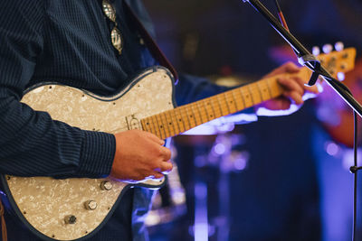 Midsection of man playing guitar on stage