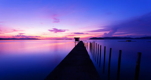 Pier over sea against sunset sky