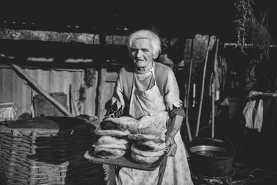 Senior woman carrying tray of baked breads