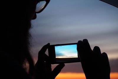 Silhouette person photographing at sunset