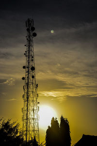 Low angle view of silhouette communications tower against sky during sunset