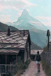 Rear view of man standing on mountain against sky