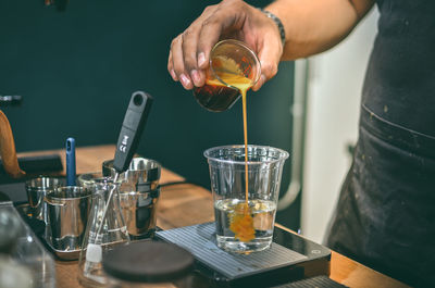 Midsection of man pouring wine in glass on table