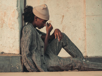 Side view of man looking away while standing against wall