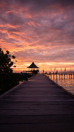 Pier over sea against sky during sunset