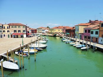 Boats moored in harbor by buildings against clear sky