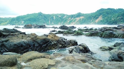 Rocks on sea shore against sky