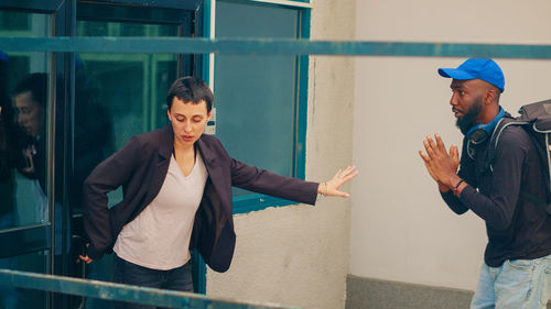 Side view of young woman standing against wall