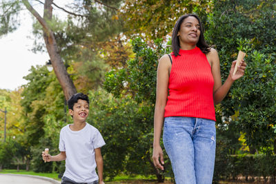 Mother and son enjoying eating ice-cream together outdoors in a park.