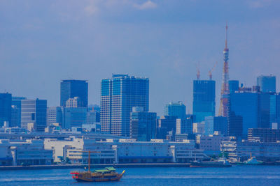 Modern buildings by sea against sky in city