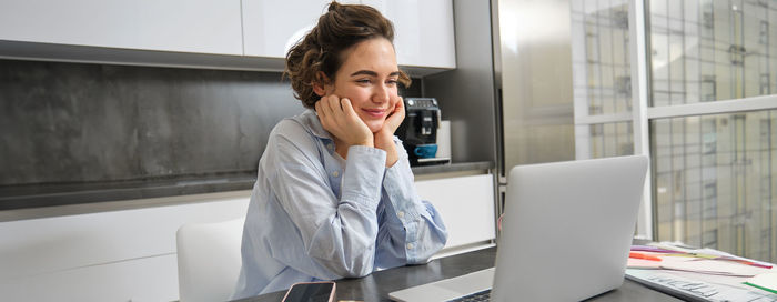 Young woman using mobile phone while sitting on table