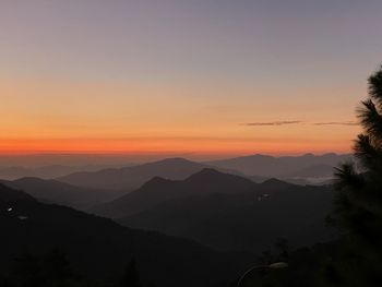 Scenic view of silhouette mountains against orange sky