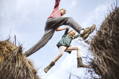 Father and daughter jumping over hay bales with excitement