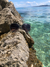 Close-up of sunglasses on rock by sea