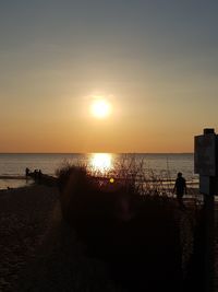 Silhouette people on beach against sky during sunset