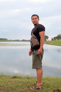 An indonesian young man standing on the field by the lake