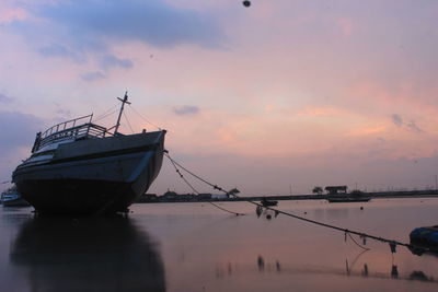 Fishing boat in sea against sky during sunset