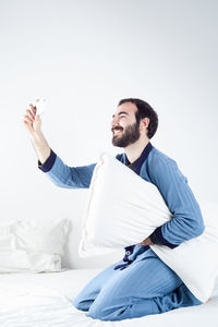 Young man looking away while sitting on bed