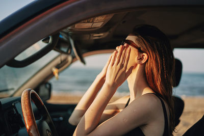 Young woman wearing sunglasses sitting in car