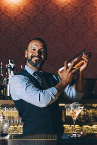 Portrait of mature bartender preparing cocktail on bar counter