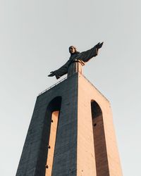 Low angle view of statue against building against clear sky