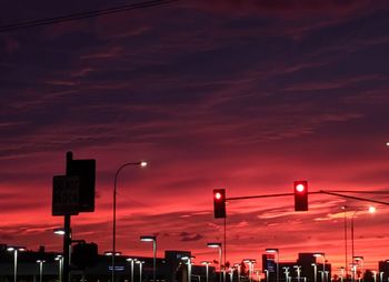 Illuminated sign against sky at sunset