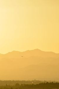 Scenic view of silhouette mountain against orange sky