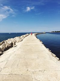 Rear view of woman on pier against sky