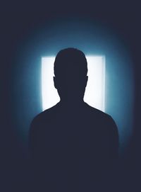 Silhouette man in darkroom towards doorway with light