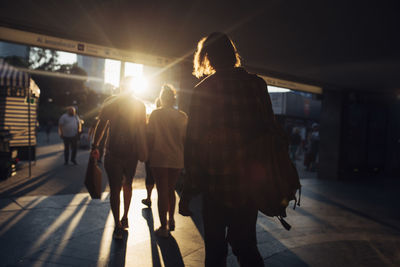 Rear view of people walking on street in city